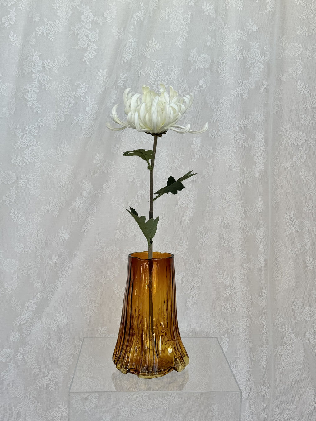 Large white artificial chrysanthemum flower from Fleuristic, showcasing realistic petals and lush green leaves.