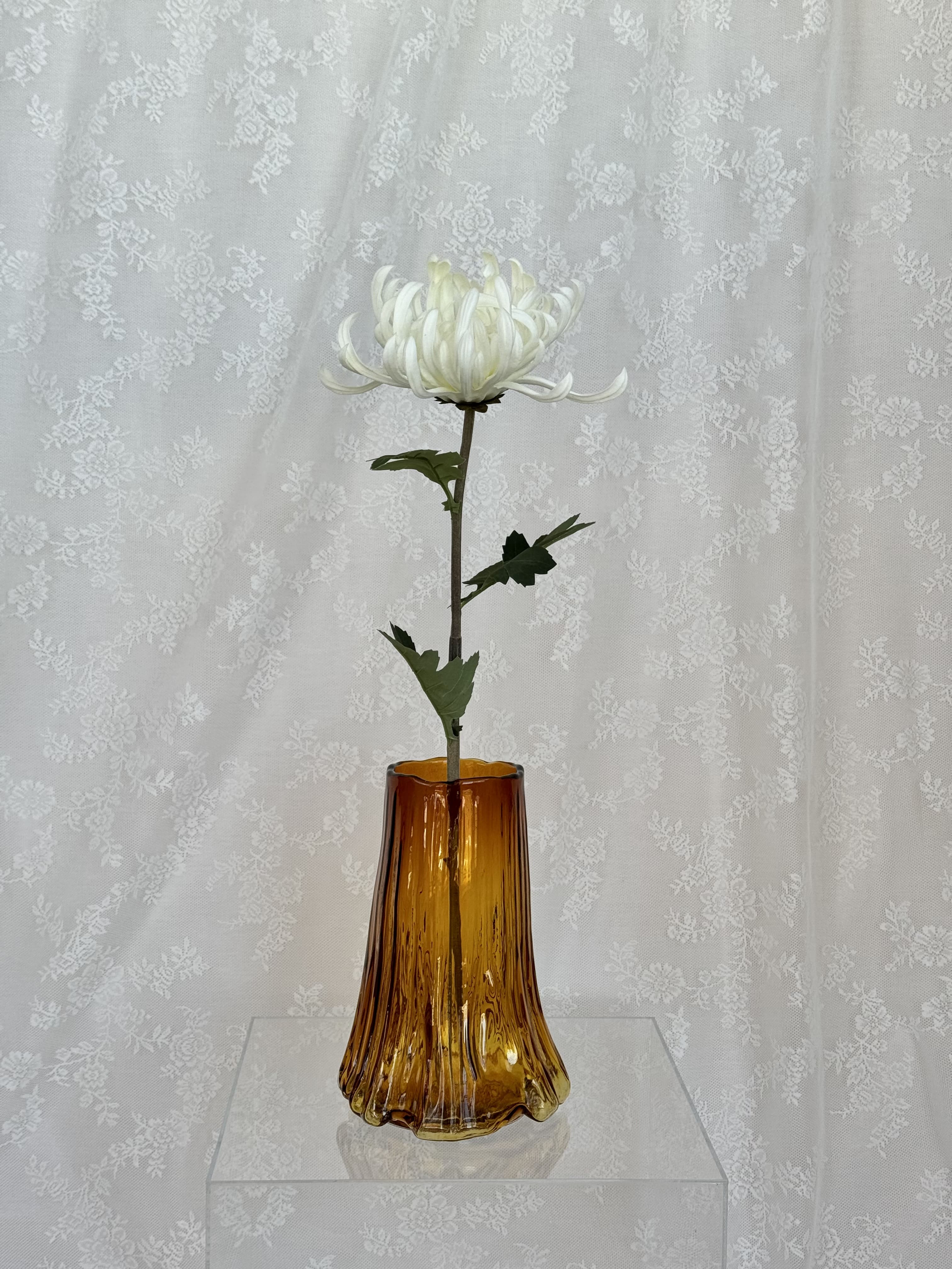 Large white artificial chrysanthemum flower from Fleuristic, showcasing realistic petals and lush green leaves.
