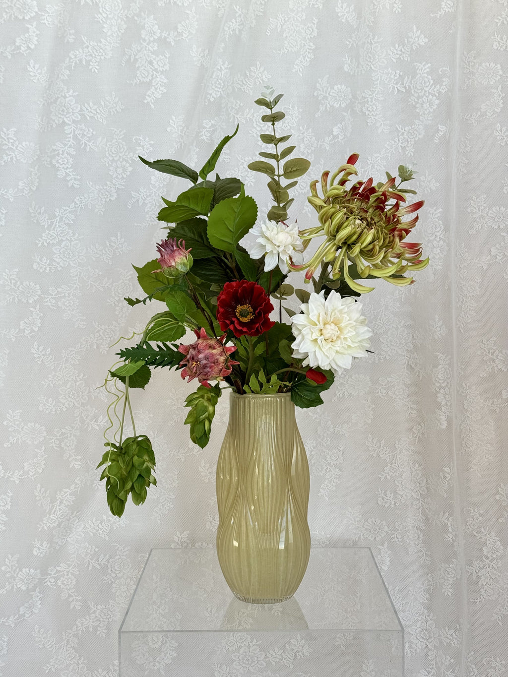 Artificial flower bouquet in red and green hues, designed by Fleuristic, resembling a lush forest scene.