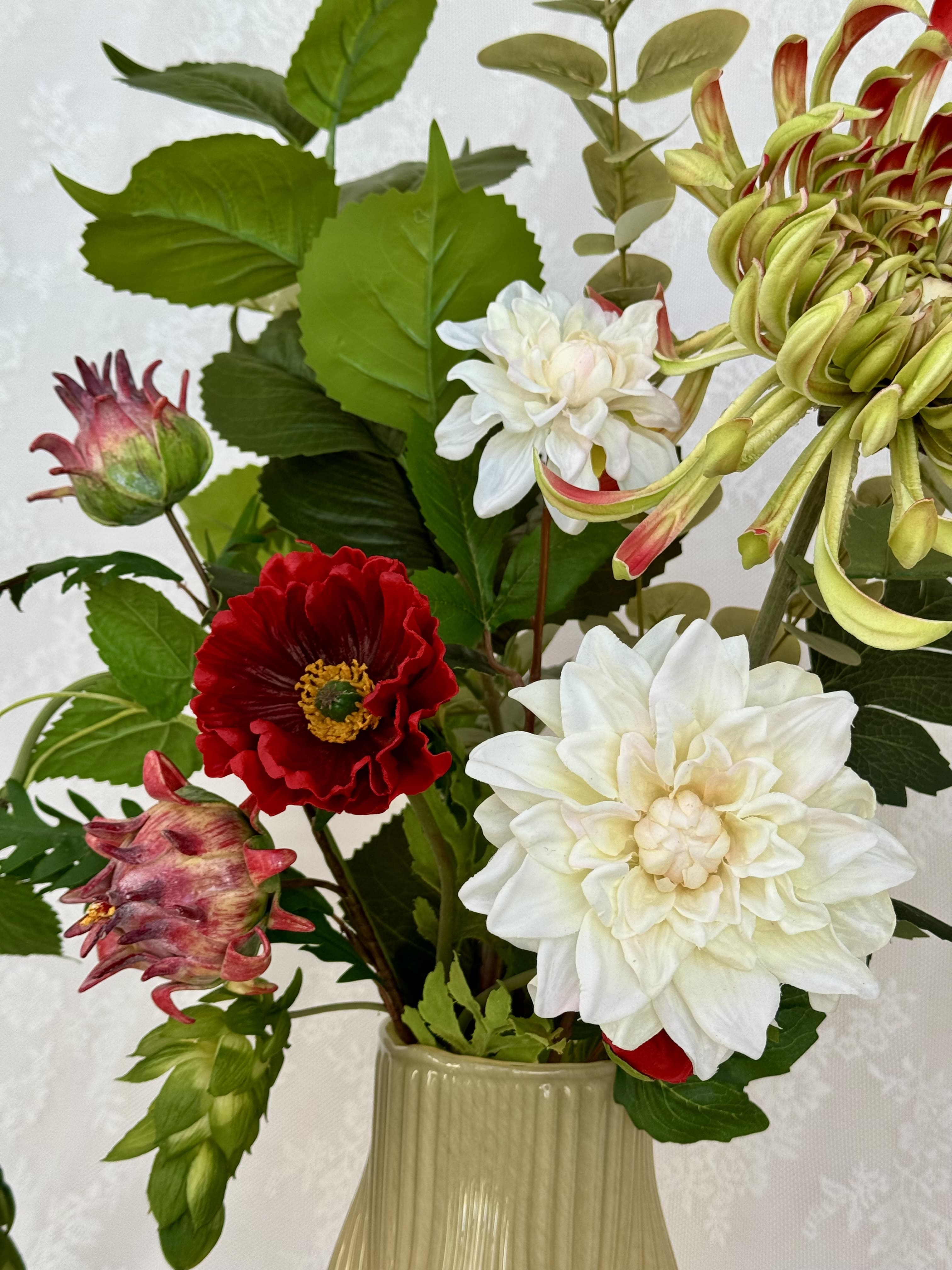 Fleuristic artificial bouquet featuring realistic reddish forest-themed flowers and lush green foliage in a natural arrangement.