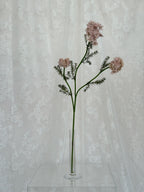 Artificial wild carrot flower by Fleuristic, showcasing vibrant orange, textured petals, and lush green foliage in a realistic design.